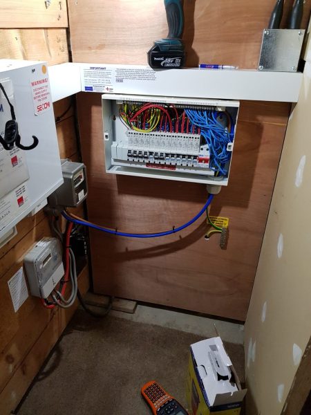 House A, Image 3.  New Fuse Board Installed. Cover of the board is open to show the neatness of the complex wiring system. Note the board sits on a new wooden back board.  All cables feeding into the board are enclosed in trunking for extra protection and tidy presentation. 