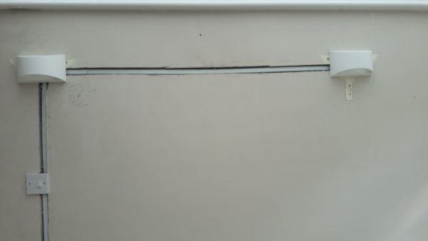 Electrical cable enclosed in plastic trunking embedded in the wall. 